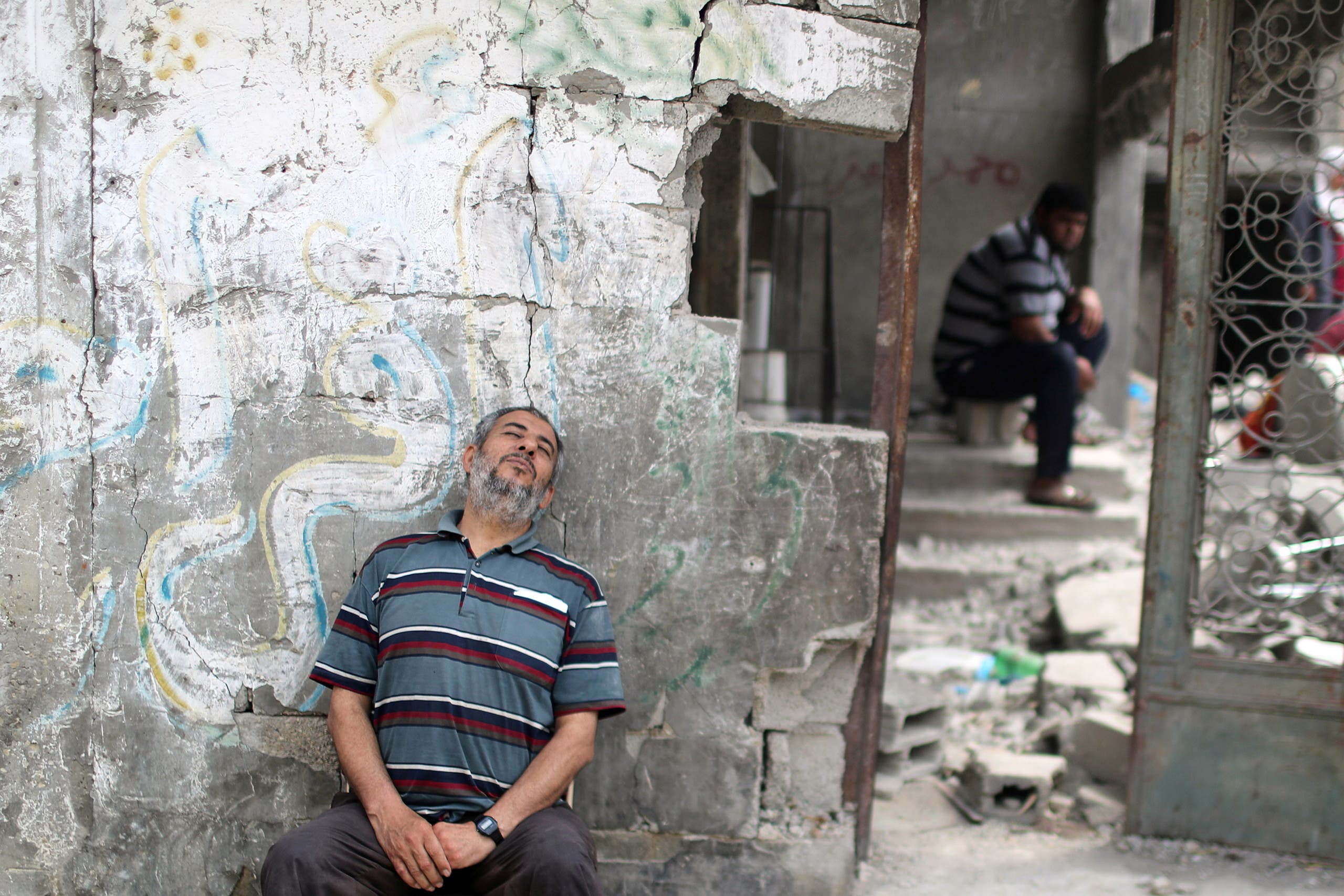 فلسطيني يجلس بجانب حطام منزله في غزة